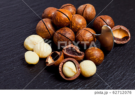 Macadamia nuts with a cleaning key on black slate, closeup. 62712076