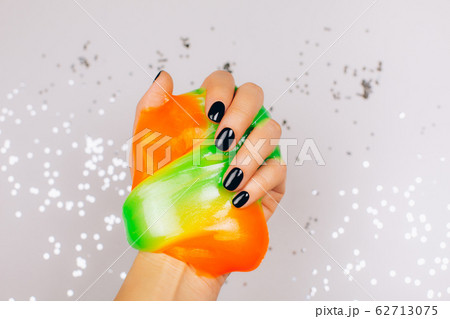 hands with black manicure holding slime 62713075
