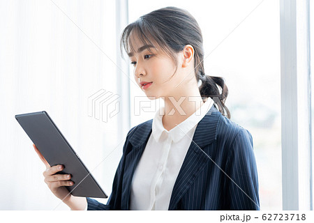 A business woman using tablet beside the window A business woman using tablet beside the window 62723718