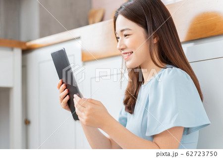 A beauty woman using tablet in the kitchen A beauty woman using tablet in the kitchen 62723750