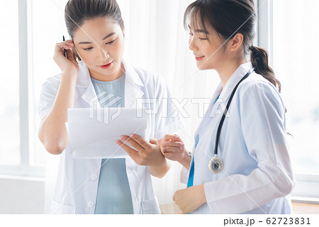 Two women doctor consulting by the window Two women doctor consulting by the window 62723831
