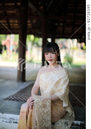 Portrait of Thai female with traditional Thai dress sitting with temple background Portrait of Thai female with traditional Thai dress sitting with temple background 62726395