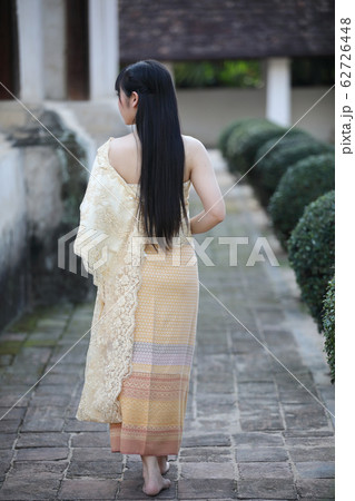 Portrait of Thai female with traditional Thai dress walking with temple background 62726448