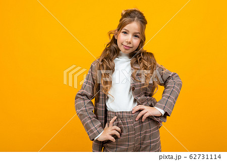 smiling european schoolgirl in a classic brown suit posing on a yellow background with copy space smiling european schoolgirl in a classic brown suit posing on a yellow background with copy space 62731114