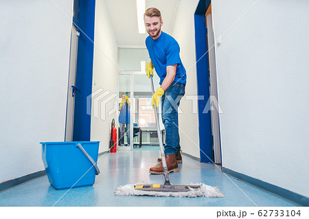 Cleaner man mopping the floor in a hall 62733104