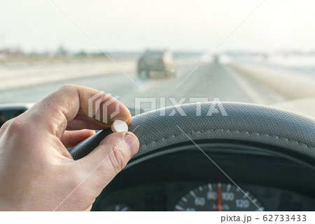 driver hand holding of pill while driving on the highway 62733433