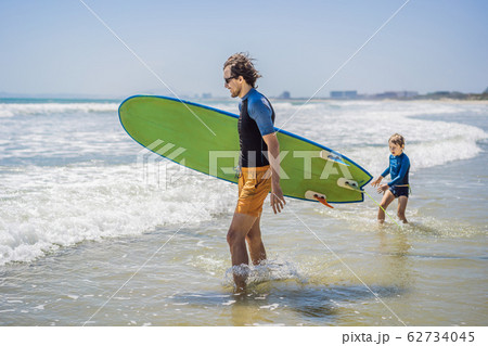 Father or instructor teaching his son how to surf in the sea on vacation or holiday. Travel and 62734045