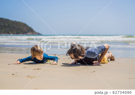 Father or instructor teaching his son how to surf in the sea on vacation or holiday. Travel and 62734090