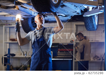 Auto Mechanic Inspecting Car on Lift 62735290