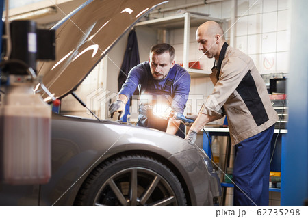 Two Mechanics Inspecting Car in Auto Shop Two Mechanics Inspecting Car in Auto Shop 62735298