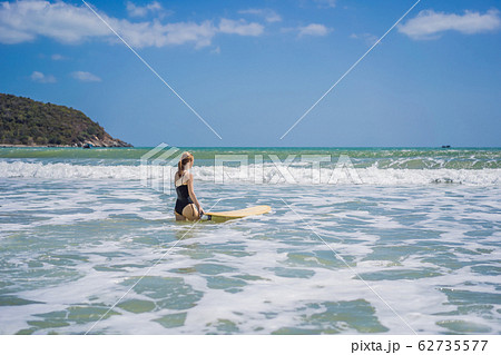 Beautiful young woman ride wave. Sporty surfer woman surfing on the background of blue sky, clouds 62735577
