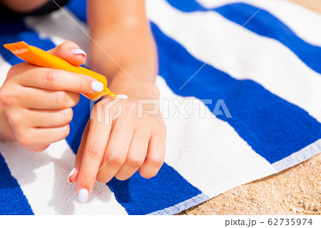 Young woman is lying on striped towel on the sand 62735974
