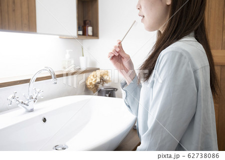 洗面化粧台で歯磨きをする若い女性 洗面化粧台で歯磨きをする若い女性 62738086