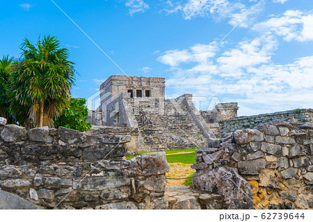 Ruins of ancient Tulum. Architecture of ancient maya. View with temple and other old buildings, houses. Blue sky and lush greenery of nature. travel photo. Wallpaper or background. Yucatan. Ruins of ancient Tulum. Architecture of ancient maya. View with temple and other old buildings, houses. Blue sky and lush greenery of nature. travel photo. Wallpaper or background. Yucatan. 62739644
