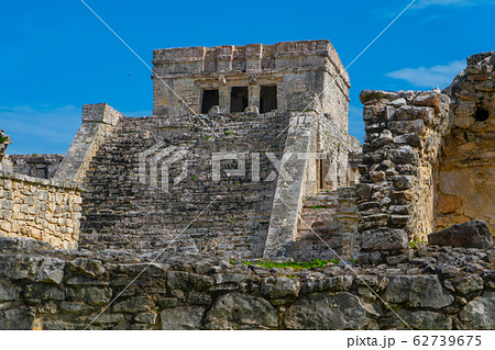 Ruins of ancient Tulum. Architecture of ancient maya. View with temple and other old buildings, houses. Blue sky and lush greenery of nature. travel photo. Wallpaper or background. Yucatan. Ruins of ancient Tulum. Architecture of ancient maya. View with temple and other old buildings, houses. Blue sky and lush greenery of nature. travel photo. Wallpaper or background. Yucatan. 62739675