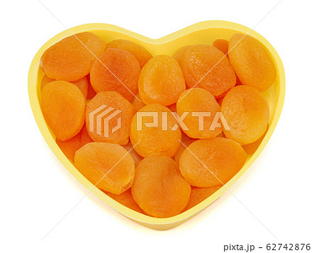 Heart shaped bowl of dried apricots isolated on white background Heart shaped bowl of dried apricots isolated on white background 62742876