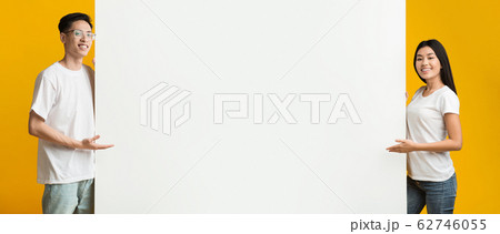 Positive asian man amd woman pointing at blank advertising board Positive asian man amd woman pointing at blank advertising board 62746055