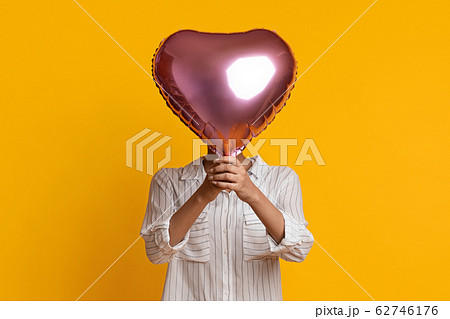 Unrecognizable Afro Woman Hiding Face Behind Heart Shaped Balloon Unrecognizable Afro Woman Hiding Face Behind Heart Shaped Balloon 62746176