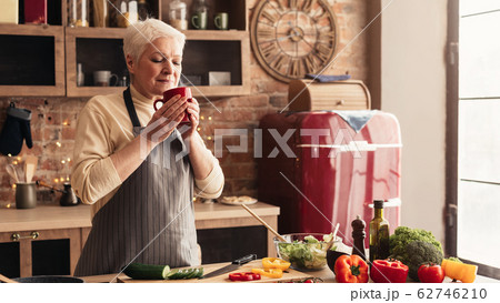 Relaxed elderly woman enjoying hot coffee in kitchen 62746210