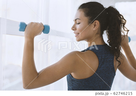 Sporty Hispanic girl on training with dumbbells in gym Sporty Hispanic girl on training with dumbbells in gym 62746215