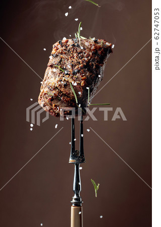 Grilled ribeye beef steak with rosemary on a brown Grilled ribeye beef steak with rosemary on a brown 62747053