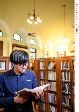 Smart Asian man student reading book in library Smart Asian man student reading book in library 62747773