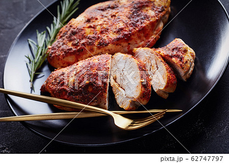 Skinless boneless chicken breasts on a black plate 62747797