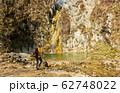 Female hiker arrives and admires a waterfall with a beautiful puddle of water 62748022