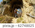 Female hiker walks through a natural mountain tunnel 62748025