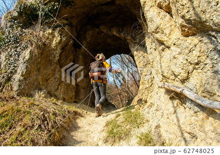 Female hiker walks through a natural mountain tunnel Female hiker walks through a natural mountain tunnel 62748025