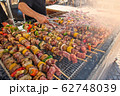 Skewers of mixed meats and vegetables cooked on the grill. 62748039