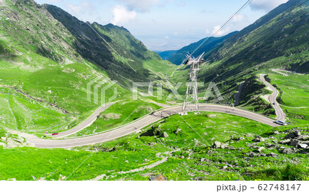 Top vew of winding road in mountains, with red car 62748147