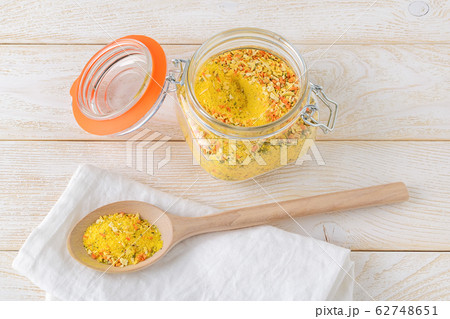 Universal seasoning in a clip top glass jar and in a large wooden spoon on a kitchen table Universal seasoning in a clip top glass jar and in a large wooden spoon on a kitchen table 62748651