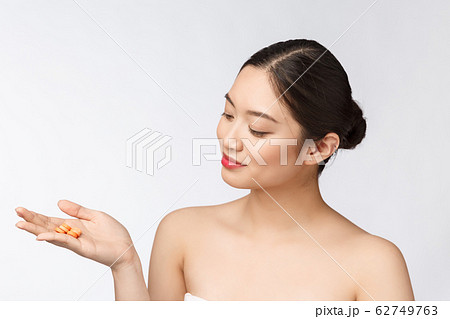 Young attractive asian woman who takes a capsule or pill. Isolated over white background. Young attractive asian woman who takes a capsule or pill. Isolated over white background. 62749763