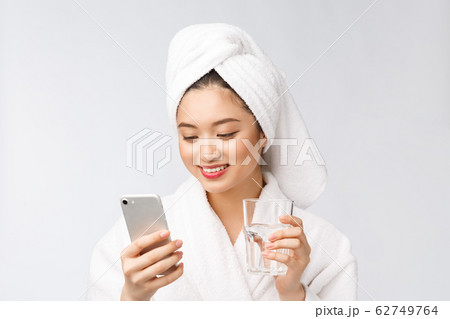 Healthy young beautiful woman drinking water, beauty face natural makeup with holding mobile phone, isolated over white background. Healthy young beautiful woman drinking water, beauty face natural makeup with holding mobile phone, isolated over white background. 62749764