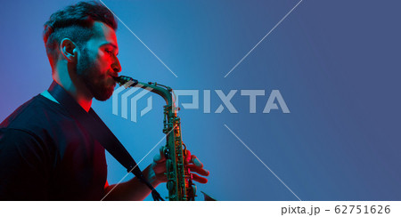 Young caucasian jazz musician playing the saxophone in neon light, flyer Young caucasian jazz musician playing the saxophone in neon light, flyer 62751626