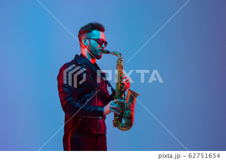 Young caucasian jazz musician playing the saxophone in neon light 62751654