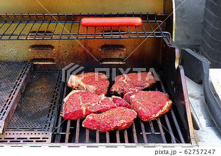 Raw seasoned steaks on a BBQ grill Raw seasoned steaks on a BBQ grill 62757247