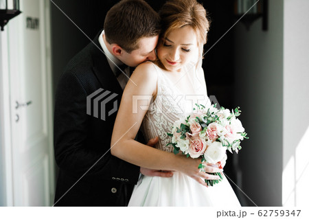 Beautiful young wedding couple posing with bouquet of flowers in hands 62759347