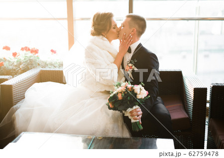 Beautiful bride and groom embracing and kissing on their wedding day Beautiful bride and groom embracing and kissing on their wedding day 62759478