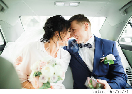 Beautiful bride and groom embracing and kissing on their wedding day in a car Beautiful bride and groom embracing and kissing on their wedding day in a car 62759771