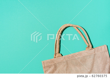 Brown cotton eco bag on blue background. Top view. Copy space. Tote reusable organic craft package. Recycle and reuse concept. Sustainable textured grossery bag Brown cotton eco bag on blue background. Top view. Copy space. Tote reusable organic craft package. Recycle and reuse concept. Sustainable textured grossery bag 62760375