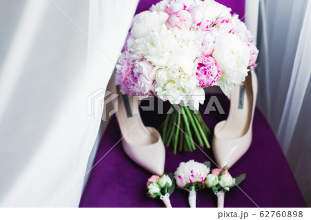 Pair of elegant and stylish bridal shoes with a bouquet with roses and other flowers 62760898