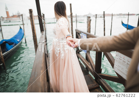 Wedding couple staying on a bridge near the canal with gondolas in Venice, Italy. Follow me Wedding couple staying on a bridge near the canal with gondolas in Venice, Italy. Follow me 62761222