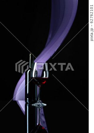 Wineglass and bottle of red wine on a black Wineglass and bottle of red wine on a black 62762101