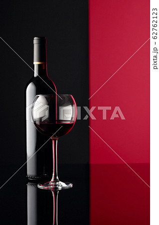 Glass and bottle of red wine on a black reflective 62762123