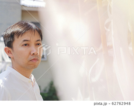 Happy Thai asian smart man wear casual white shirt is peeking back the white soft lace fabric curtain on sunshine, relaxing timesummer day. Asia Lifestyle chill out at outdoor. He looking for someone Happy Thai asian smart man wear casual white shirt is peeking back the white soft lace fabric curtain on sunshine, relaxing timesummer day. Asia Lifestyle chill out at outdoor. He looking for someone 62762948