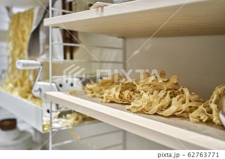 Many raw noodle with pasta maker machine indoors 62763771