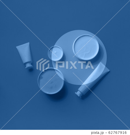 Cosmetics, skin care, beauty, body treatment concept. White cosmetic jar, tube, bottle and tropical monstera leaf over monochrome color background. Trendy blue and calm color. 62767916