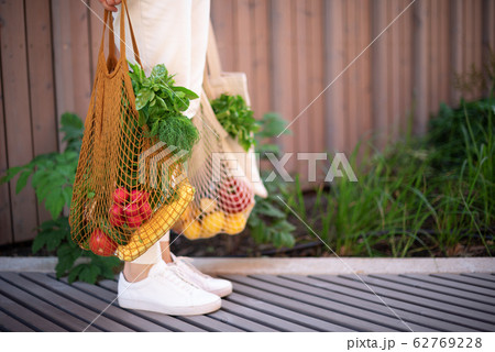 Girl holding mesh shopping bag and cotton shopper with vegetables without plastic bags, wooden background. Zero waste, plastic free concept. Sustainable lifestyle. Banner. 62769228